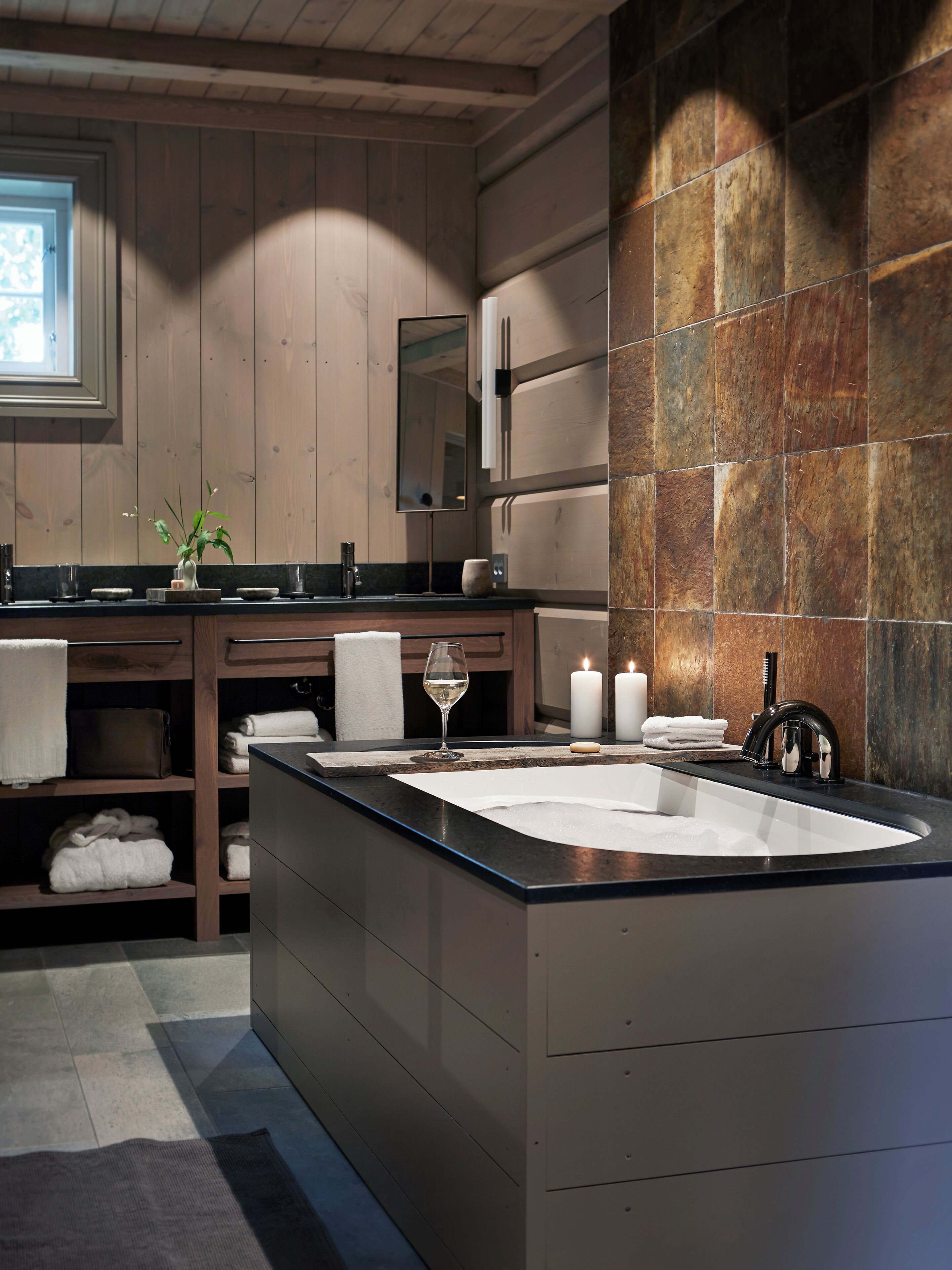 Un bagno moderno con un lavandino ampio, mobili in legno e uno schienale in pietra.
