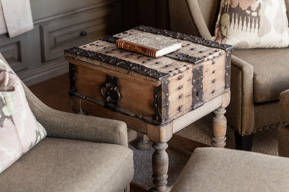 Un dormitorio acogedor con cabecera de madera, cama con sábanas blancas, una mesita de noche con un libro y una lámpara.