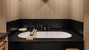 A modern bathroom with a black bathtub, wooden accents, and a deer head mounted on the wall.
