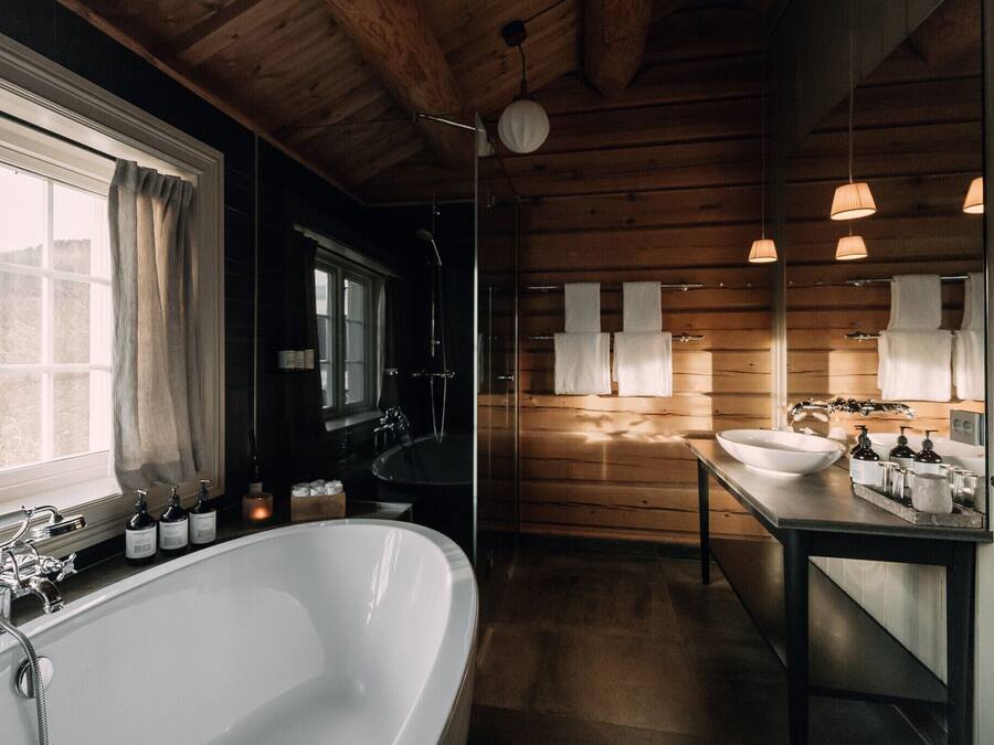 Un baño moderno con una bañera independiente, dos lavabos y paneles de madera.