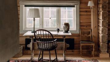 Una habitación acogedora con una mesa de madera, una silla, una lámpara y una ventana con vistas.