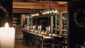 A long dining table set for a meal with chairs, candles, and a chandelier. - Storfjord Hotel (Ålesund)