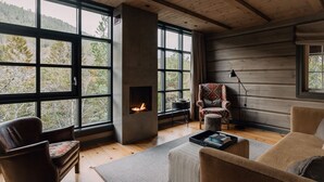 A cozy cabin interior with a fireplace, large windows, and wooden floors. - Storfjord Hotel (Ålesund)