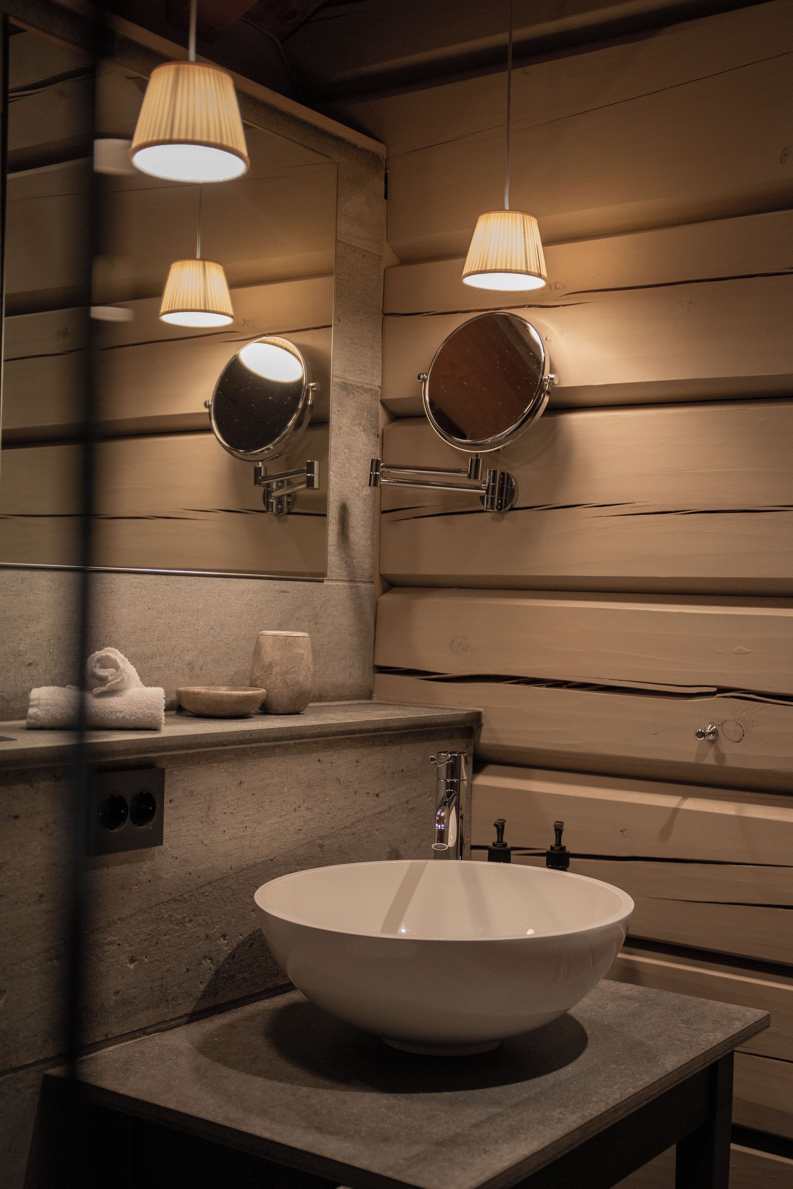 A bathroom with a large vessel sink, two wall-mounted mirrors, and pendant lighting.