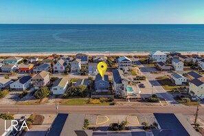 An aerial view of a coastal residential area with houses, a road, and a beach. - Blue Crab Bungalow – Stay, Play, Repeat! (Surf City)