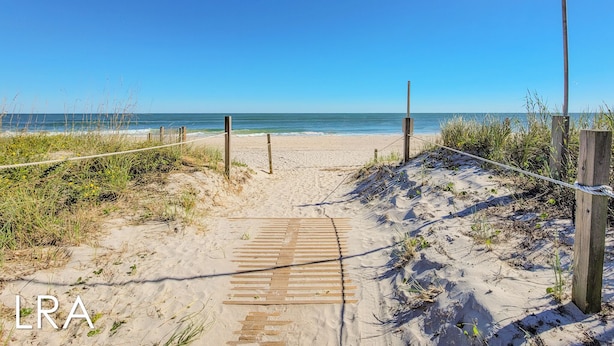 A sandy beach path leading to the ocean with wooden planks and a rope barrier. - Blue Crab Bungalow – Stay, Play, Repeat! (Surf City)