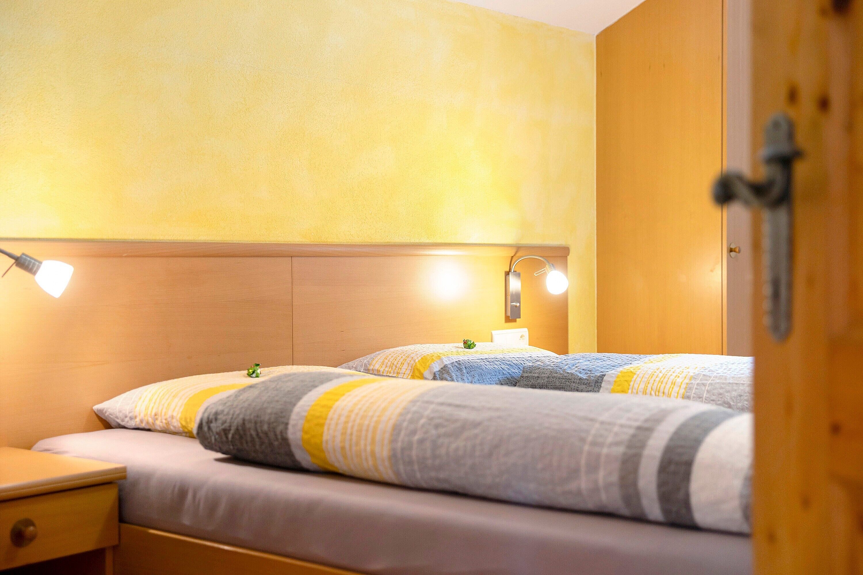 A hotel room with two beds, bedside lamps, and a wooden wardrobe.
