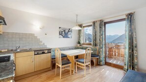 Une cuisine avec un coin repas, des meubles de rangement en bois, un évier et une fenêtre donnant sur les montagnes.