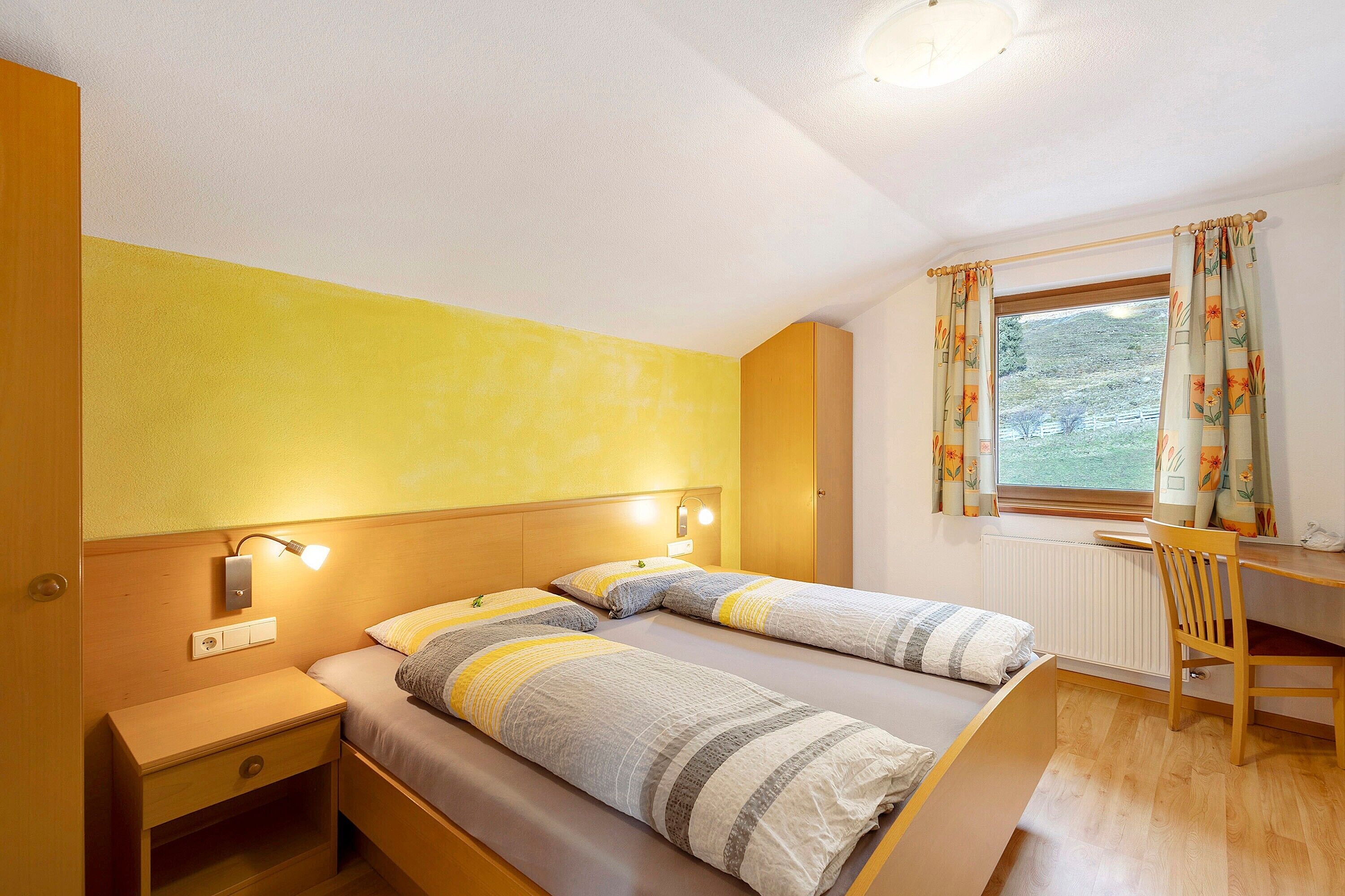 Ein Schlafzimmer mit zwei Betten, einem Schreibtisch und einem Fenster mit Vorhängen.