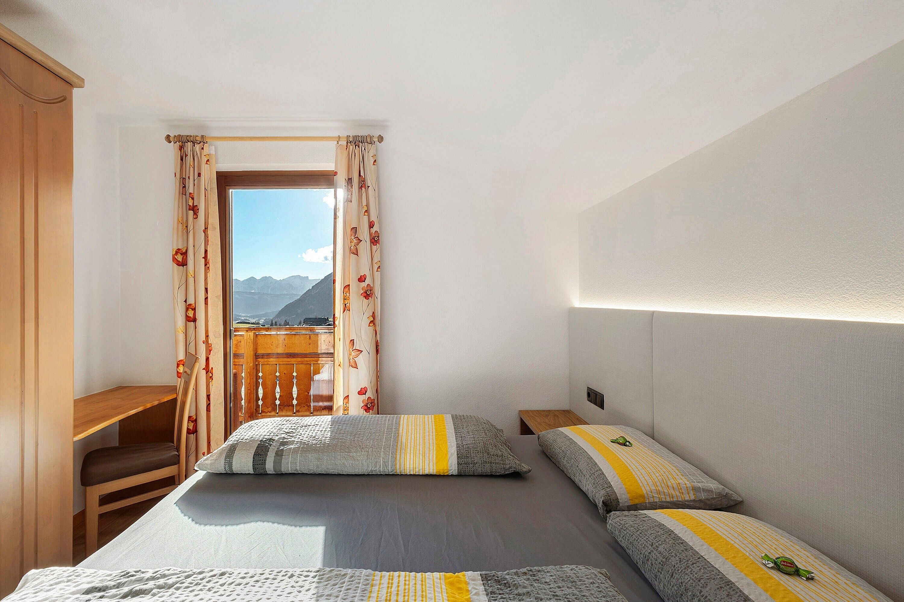 A bedroom with a bed, a desk, and a view of mountains.
