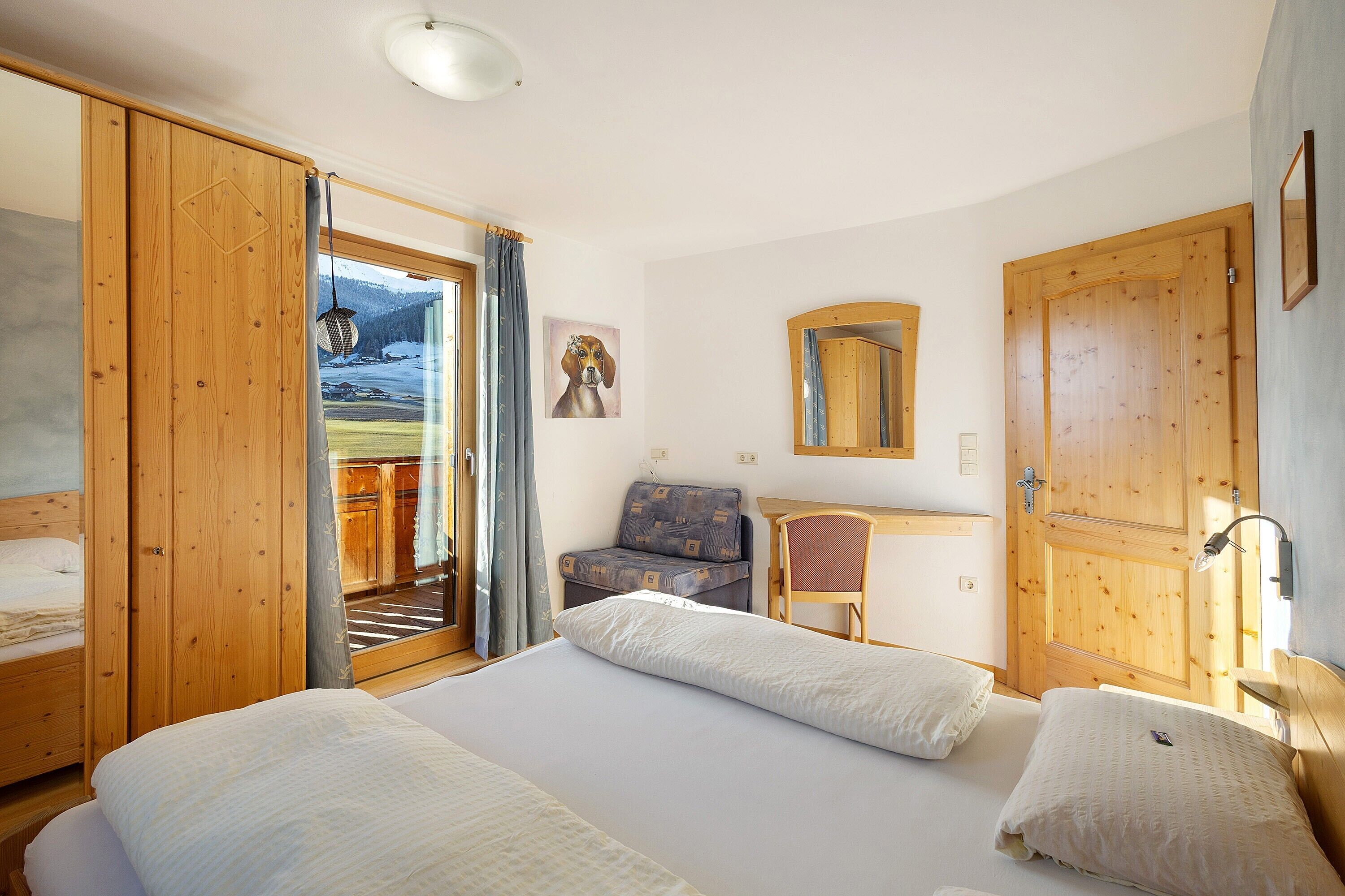 Una camera da letto con un letto, una sedia, una scrivania e un'ampia porta di legno.
