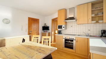 Une cuisine compacte dotée de meubles en bois, d’un four à micro-ondes, d’un four traditionnel et d’un coin repas avec une table et des chaises.