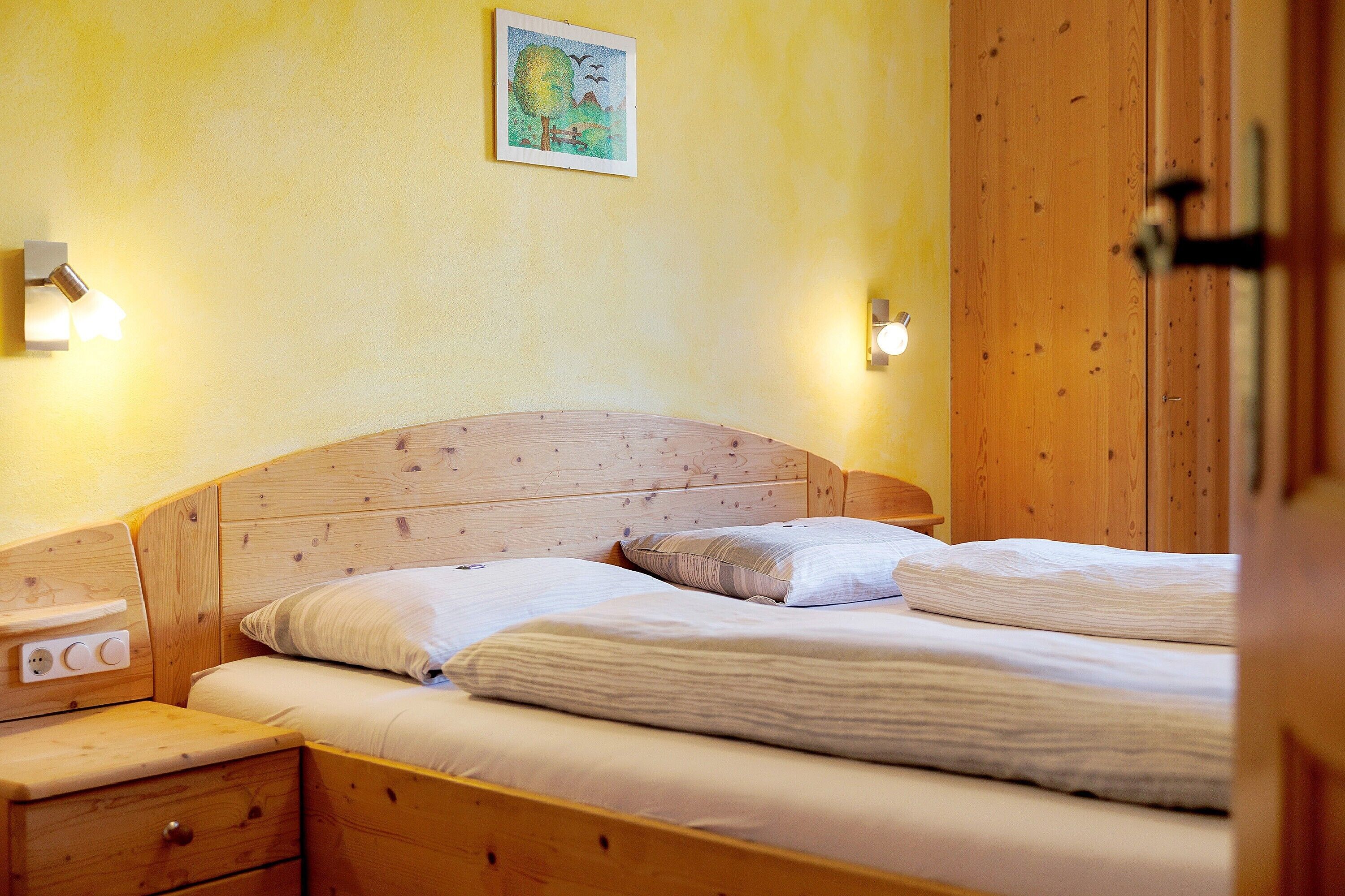 A wooden bed with two pillows and a nightstand with a drawer.