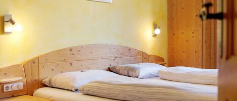 A wooden bed with two pillows and a nightstand with a drawer.