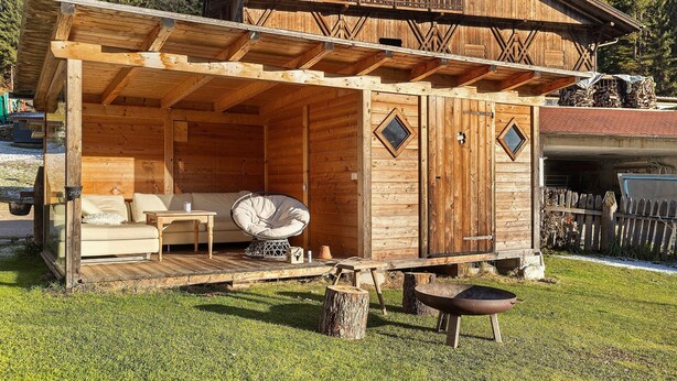 Eine Holzhütte mit Balkon, einer Couch und einem Esstisch.