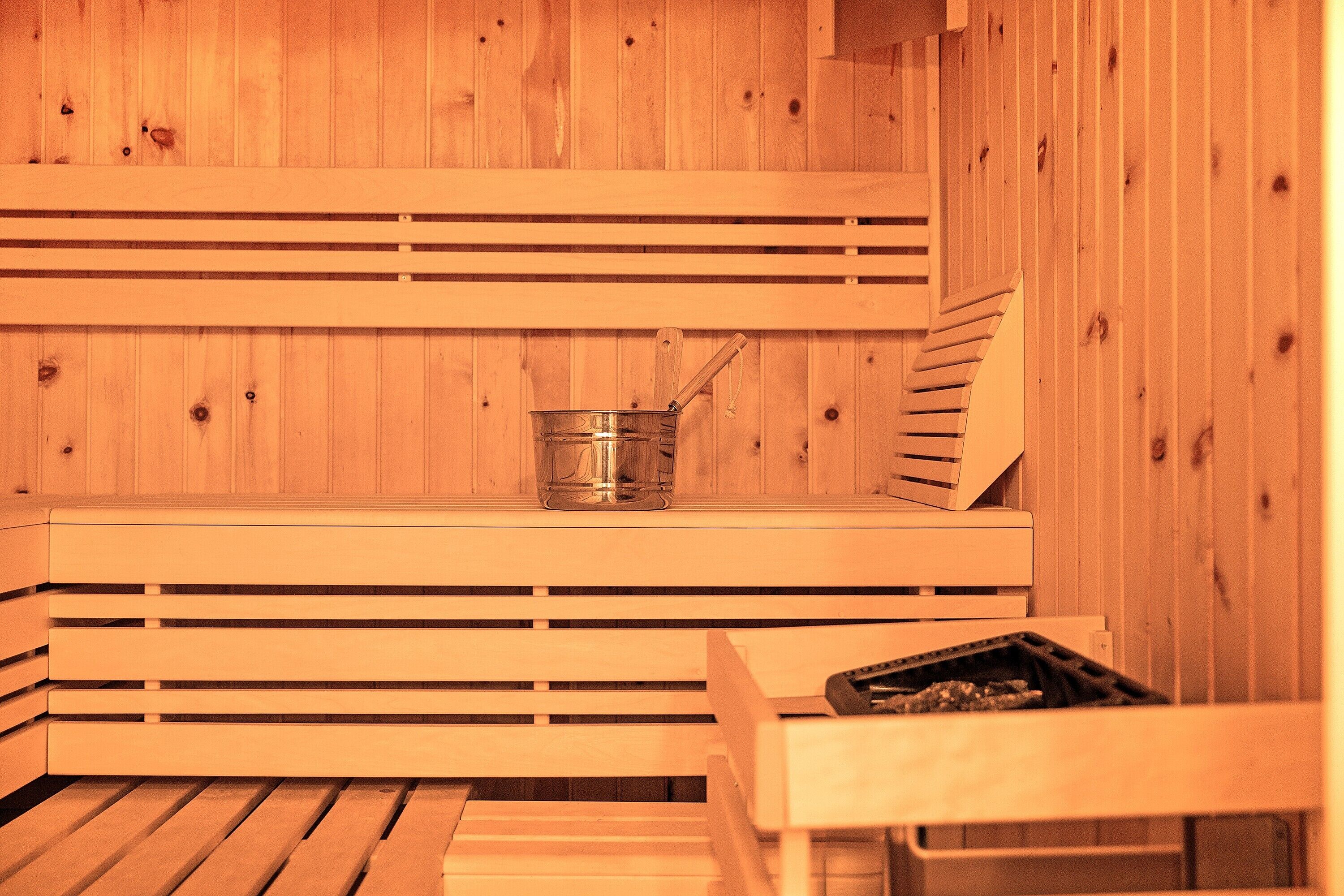 Una sauna de madera con bancos y un cubo de metal.