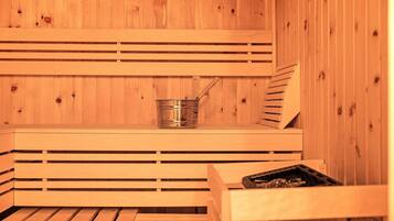 Una sauna in legno con panche e un catino di metallo.