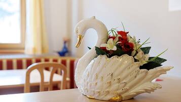 Een witte, zwaanvormige vaas met gouden accenten en een boeket rode en witte bloemen op een tafel.