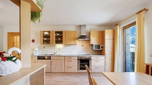 Eine Küche mit Holzausstattung, einer Mikrowelle, einem Backofen und einem Essbereich mit Tisch und Stühlen.
