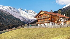 Eine Holzhütte mit rotem Ziegeldach, Holzbalkonen und Blick auf verschneite Berge.
