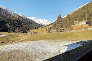 Eine gebirgige Landschaft mit schneebedeckten Gipfeln, blauem Himmel und einem eingezäunten Feld.