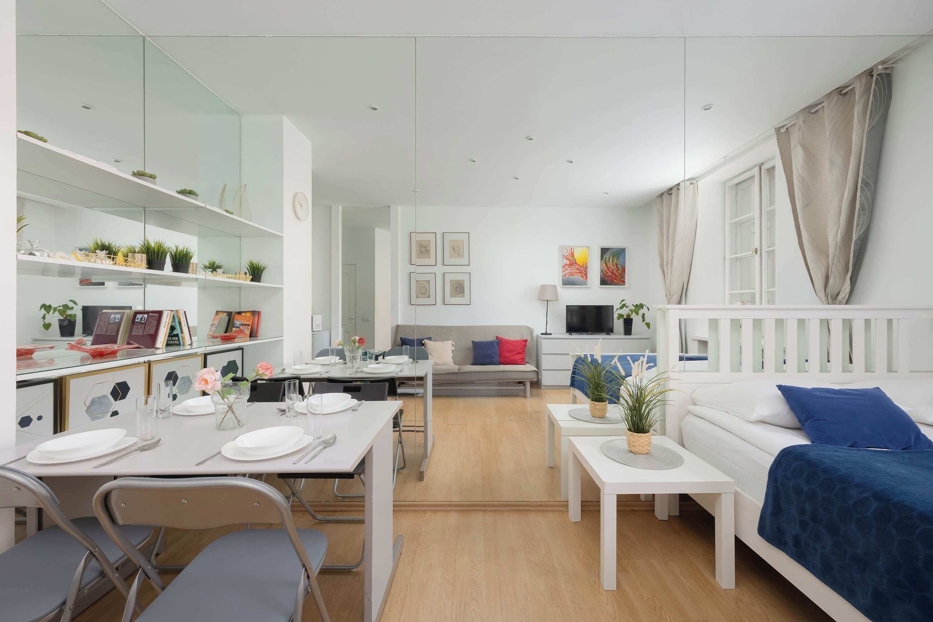 Een moderne, goed verlichte woonkamer met een eethoek, een bank en een televisie.