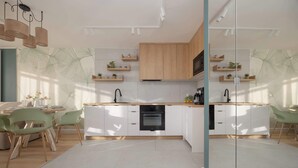 Una cocina moderna con armarios blancos, encimeras de madera y un horno empotrado. Hay sillas verdes y una mesa de comedor con un jarrón de flores.