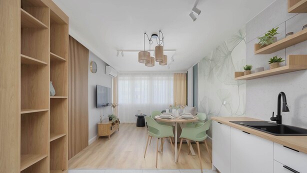 Una cocina moderna con armarios de madera, una zona de comedor con una mesa redonda y sillas, y un lavamanos negro.