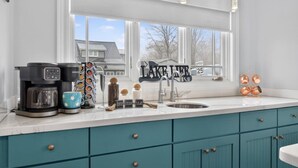 A kitchen with a coffee maker, a mug, a sugar container, a cream container, and a coffee grinder. - Lake Days, Bonfires & Endless Memories (Coldwater)