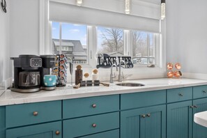 A kitchen with a coffee maker, a mug, a sugar container, a cream container, and a coffee grinder. - Lakefront, Kayaks, Bonfires &  Endless Memories (Coldwater)