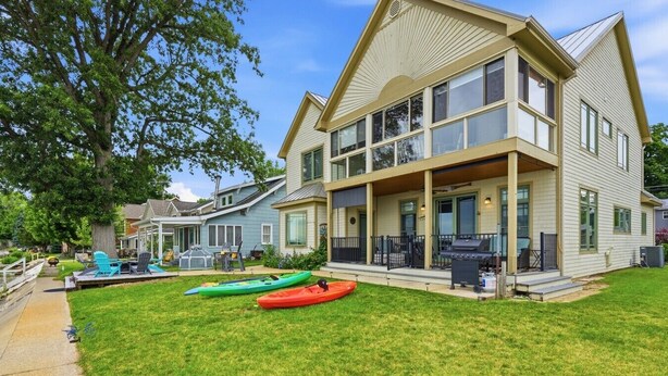 A two-story house with a large porch, a grill, and kayaks in the yard. - Lake Days, Bonfires & Endless Memories (Coldwater)
