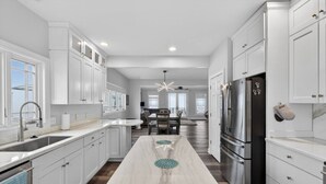 A modern kitchen with white cabinetry, a marble countertop, and a stainless steel refrigerator. - Lake Days, Bonfires & Endless Memories (Coldwater)