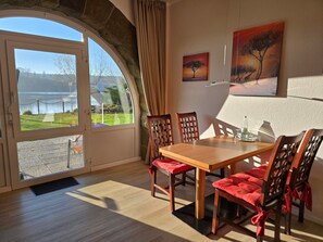 Un comedor con una mesa y sillas, vistas a través de un ventanal y una obra de arte en la pared.