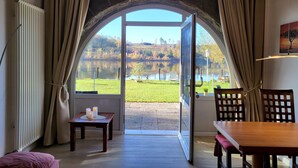 Una stanza con un'ampia finestra ad arco, un tavolo con candele e vista su un lago e alberi.