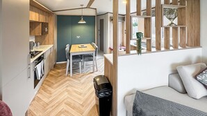 Ein kompakter Wohnraum mit einer Küche, einem Essbereich und einer Sitzecke mit Sofa und Kissen.
