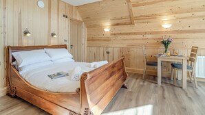 Una habitación con paneles de madera, una cama, una mesa con sillas e iluminación en las paredes.