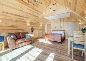 A wooden interior with a sofa, a bed, and a dining table.