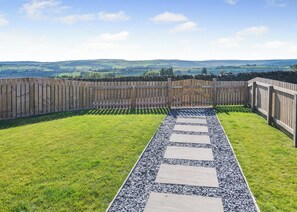 A fenced backyard with a gravel path leading to a wooden gate. - 1 bedroom accommodation in Ripponden (Ripponden)
