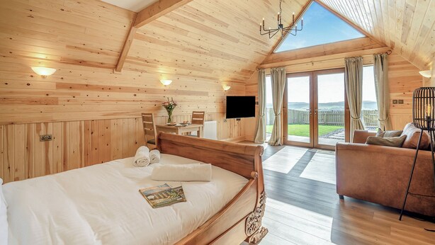 A wooden cabin with a large bed, a TV, a sofa, and a view of the outdoors. - 1 bedroom accommodation in Ripponden (Ripponden)