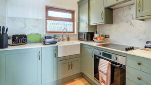 A kitchen with light green cabinets, a marble countertop, a built-in oven, and a window above the sink. - 1 bedroom accommodation in Ripponden (Ripponden)
