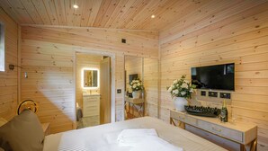 Una habitación con paneles de madera, una cama, un televisor, un tocador y un espejo.