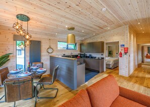 Un intérieur moderne comprenant un coin repas, une cuisine et un espace de vie, avec des plafonds en bois et un mobilier contemporain.