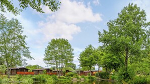Zona de cabañas junto al lago, con cabañas de madera, un lago tranquilo y vegetación circundante.