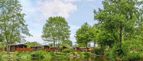Zona de cabañas junto al lago, con cabañas de madera, un lago tranquilo y vegetación circundante.