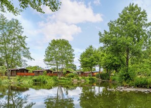 A lakeside cabin area with wooden cabins, a calm lake, and surrounding greenery.
