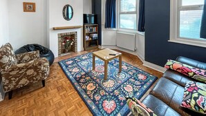 Una sala de estar con chimenea, un sofá, una mesita de centro y una estantería.