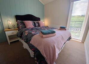 Ein Schlafzimmer mit Bett, Nachttisch und Fenster mit Jalousien.