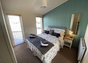 A bedroom with a bed, bedside tables, a mirror, and a radiator.