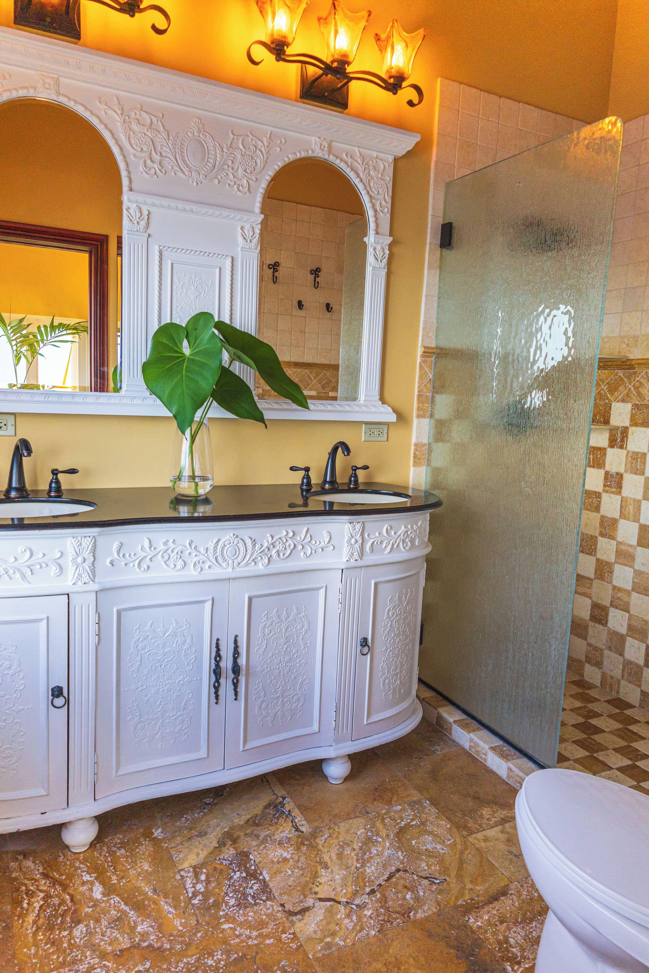 A bathroom with a white vanity, two sinks, a large mirror, and a glass shower enclosure.
