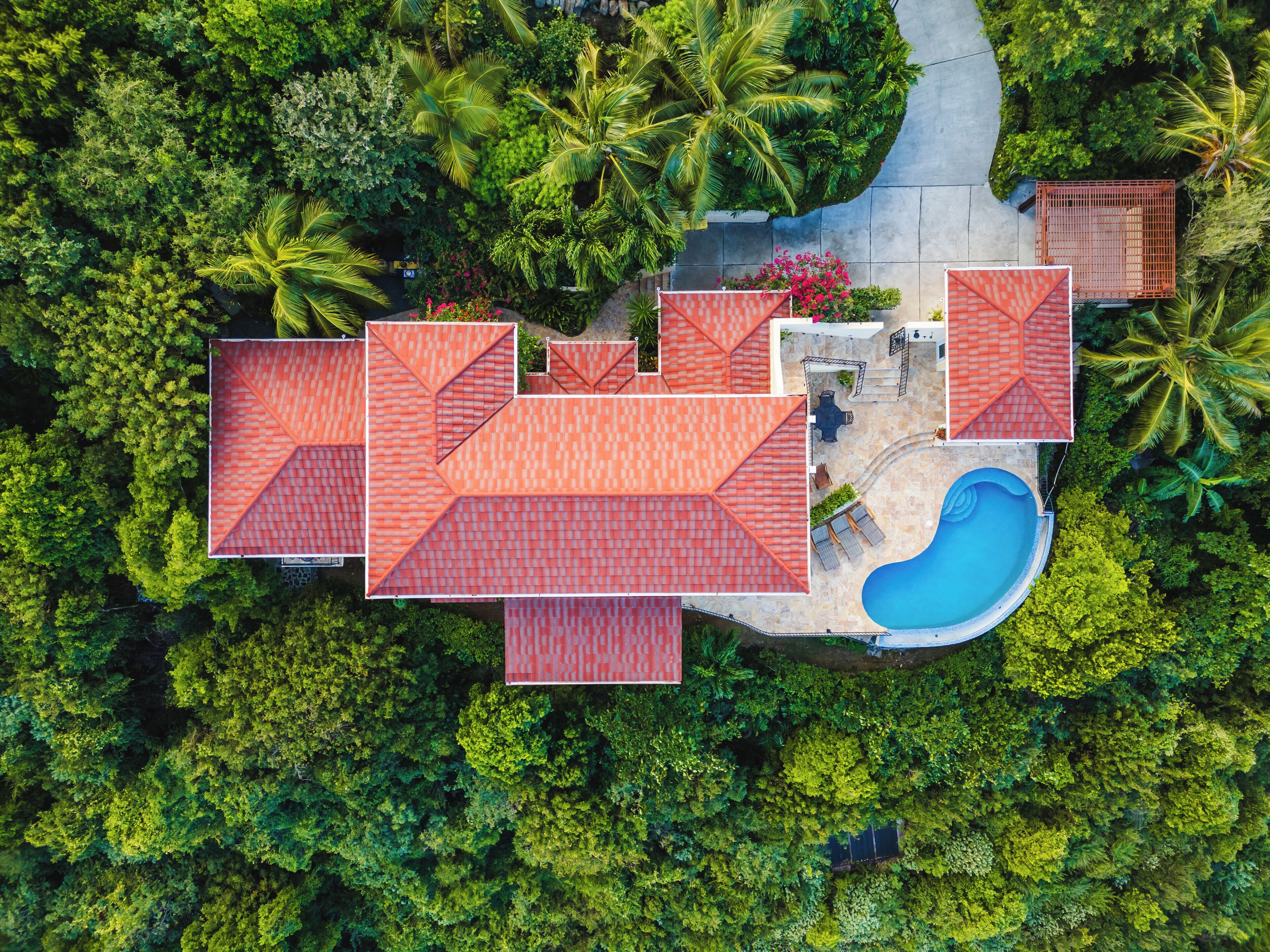 Vue aérienne d’un complexe hôtelier comprenant plusieurs bâtiments, une piscine et une végétation luxuriante.